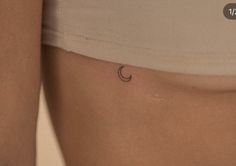 a woman's stomach with a small crescent tattoo on it