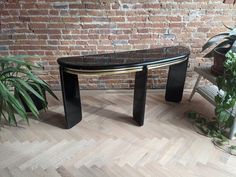 a black marble top bench in front of a brick wall with potted plants on it