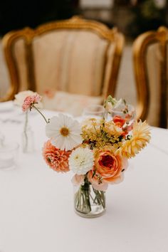 a vase filled with flowers sitting on top of a table next to two empty chairs