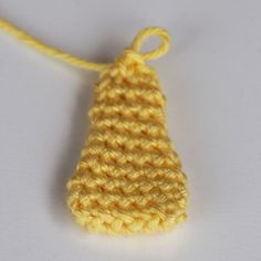 a yellow crochet ornament hanging from a string on a white surface