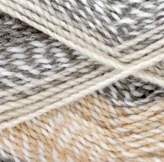 two skeins of white and grey yarn on top of each other, one is brown