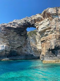 the water is crystal blue and clear, with an arch in the rock formation above it