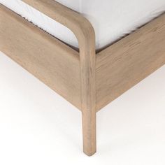 a wooden bed frame with white sheets and pillows on it's sides, viewed from the bottom