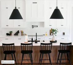 three black chairs sit at the center of a kitchen island in front of white cabinets