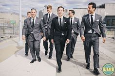 a group of men in suits walking down a sidewalk