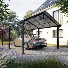 a car parked in front of a house with a metal roof on gravel ground next to trees and bushes