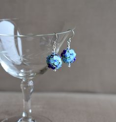 These Dark and Light Blue Raised Floral Lampwork Glass Bead with Crystal earrings are great for every day or an evening out!   An excellent Mother's Day Gift, Birthday Gift, Holiday or anytime earring!   The earrings have a 1 1/2" drop, and Sterling Silver ear wires.  The floral glass bead is approximately 1/2" (15mm)  in diameter.  The raised blue glass flowers (with a tiny pink or blue center and green leafs) are on a lampwork glass bead with a black core. The blue crystals are 2 mm.   The earring comes with sterling silver earwires. However, If you need Niobium ear wires for allergy purposes, please send a message to me with your order/payment. Niobium wire offers outstanding qualities, including being non-reactive with those who have sensitive skin or metal allergies.  The niobium earw Blue Wire-wrapped Glass Earrings, Blue Wire Wrapped Glass Earrings, Blue Glass Wire Wrapped Earrings, Blue Wire Wrapped Beaded Earrings, Blue Wire Wrapped Beaded Earrings For Party, Blue Wire Wrapped Round Beaded Earrings, Blue Round Wire Wrapped Beaded Earrings, Blue Czech Glass Earrings For Party, Blue Czech Glass Wire Wrapped Beaded Earrings