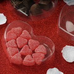 there are many heart shaped candies in the plastic bowl on the table next to each other