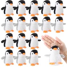 a hand is holding a small penguin plush toy in front of a group of penguins