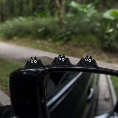 the rear view mirror is decorated with two black cats on it's head and eyes