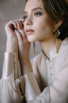 a woman with her hand on her chin and wearing gold earrings, posing for the camera