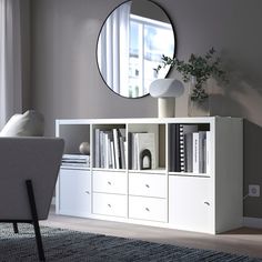 a white bookcase with drawers and a round mirror on the wall