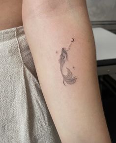 a woman's arm with a small fish tattoo on the left side of her arm