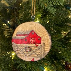 a wooden ornament hanging from a christmas tree with a red barn on it