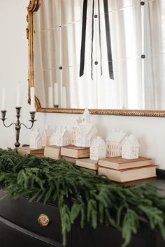 a christmas mantle with candles and small houses on it in front of a large mirror