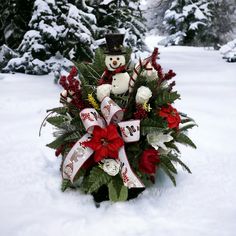 a christmas wreath with a teddy bear and poinsettis in the snow