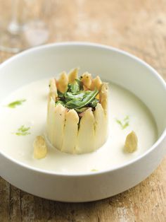 a white bowl filled with food and garnished in sauce on top of a wooden table