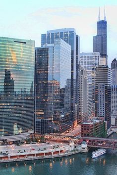 the city is full of tall buildings and boats on the water in front of them