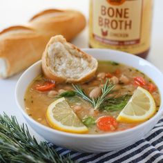 a bowl of soup with bread and lemon slices