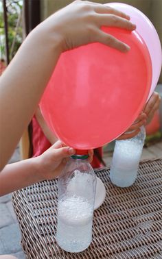 someone holding a red frisbee over two plastic cups