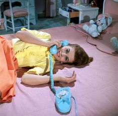 a woman laying on the floor talking on a telephone