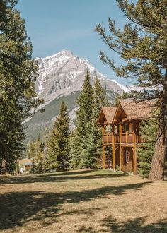 a wooden cabin in the woods with mountains in the background