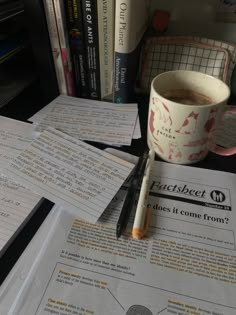 a cup of coffee and some papers on a desk