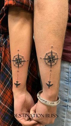 two people holding hands with compass tattoos on their arms, both wearing matching bracelets