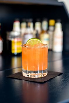 a close up of a drink on a bar with alcohol bottles in the back ground