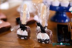 two chocolate candies wrapped in cellophane and tied with black ribbon sitting on a wooden table