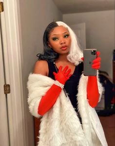 a woman taking a selfie with her cell phone wearing red gloves and white fur vest