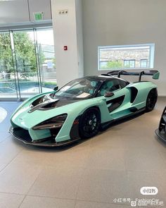 a blue and black sports car is parked in a showroom with two other cars