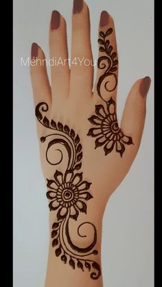 a hand with henna on it that has flowers and swirls painted on it