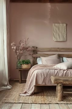 a bed sitting in a bedroom next to a wooden bench and window with curtains on it