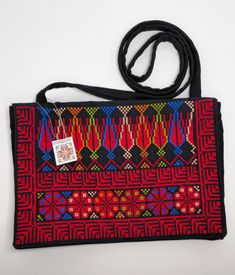 a black bag with red, blue and green designs on the front has a tag hanging from it