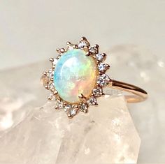 an opal and diamond ring sitting on top of a rock