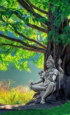 the statue is sitting in front of a tree