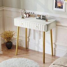 a white table with gold legs in a living room next to a painting on the wall