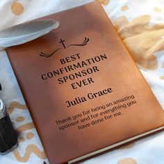 a brown book with writing on it next to a pair of eyeglasses and a pen