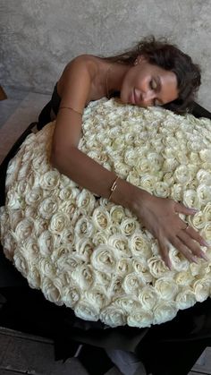 a woman laying on top of a large white rose covered pillow with her hands resting on it