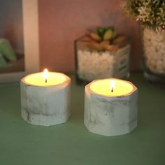 two white candles sitting on top of a green table