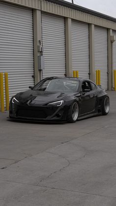 a black sports car parked in front of a storage building