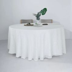 a white table with two chairs and a plant in a vase on the table top