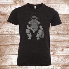 "This shirt features a baseball catcher, and is printed with solid permanent heat transfer vinyl. When ordering, please include the following: 1. Shirt color (main photo is a Bella heather black tshirt) 2. Any print color changes requested Please note that if this information is not provided in the notes, the shirt will be printed and sent as it appears in the MAIN photo Available Shirt styles: Youth T-Shirt - Sizes XS - XL Adult T-shirts - Sizes S-2X -------Design changes are subject to additio Black T-shirt With Heat Transfer Vinyl For Sports, Sports Sublimation Design T-shirt With Screen Print, Black T-shirt For Sports Season With Heat Transfer Vinyl, Black Sports Tops With Heat Transfer Vinyl, Sporty Graphic Print Shirt For Football Season, Short Sleeve Sports T-shirt With Heat Transfer Vinyl, Black T-shirt With Baseball Screen Print, Sporty Short Sleeve T-shirt With Heat Transfer Vinyl, Sporty Short-sleeve T-shirt With Heat Transfer Vinyl