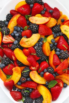 a white bowl filled with sliced fruit and berries