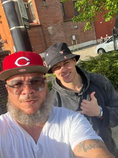 two men standing next to each other on the street