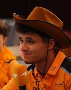 a man wearing a cowboy hat and holding a microphone in front of two other men