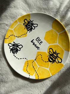 a plate with bees painted on it sitting on a white surface next to a towel