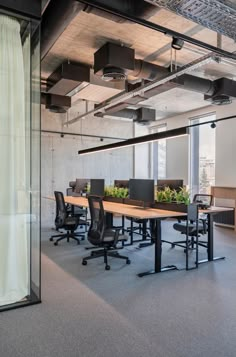 an empty conference room with desks and plants in the center, along with other office furniture