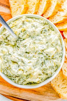 a white bowl filled with spinach dip surrounded by sliced bread